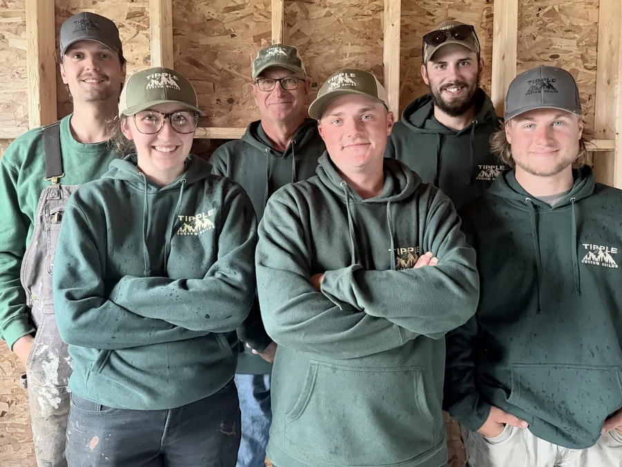 Six of the Tipple Custom Builds crew in matching green company hoodies and caps, standing together in front of a framed wall. Back row: Skyler Kato, Scott Tipple and Bradley Tipple. Front row: Ani Zwicker, Josh Reidl and Connor Acker.