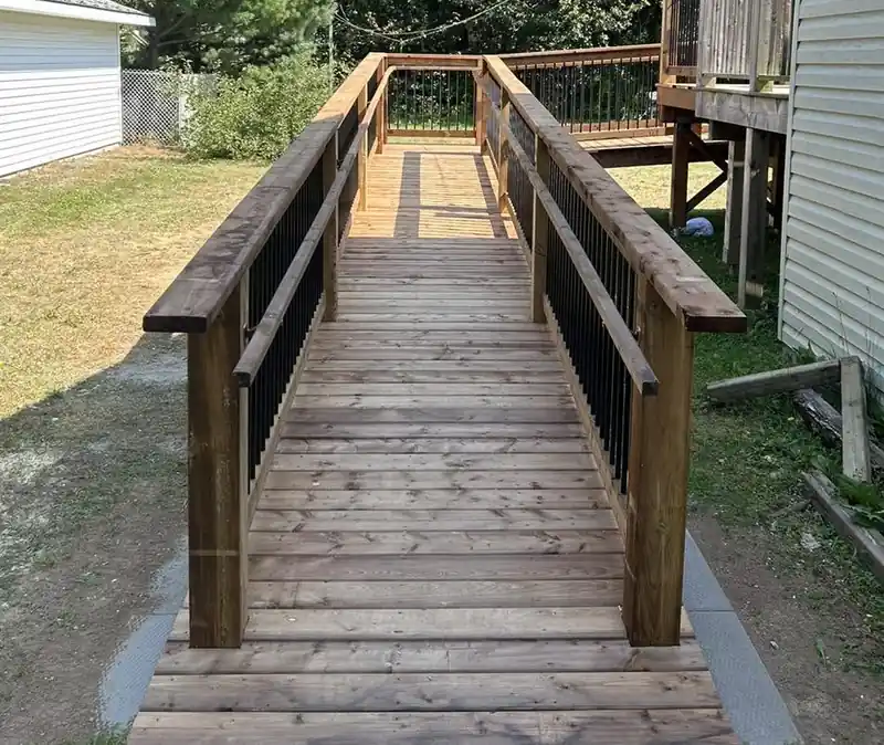 A timber accessibility ramp with a handrail running up to a house door.