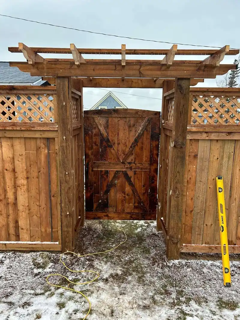 A cedar arbour gate with a braced batten door built into a privacy fence.
