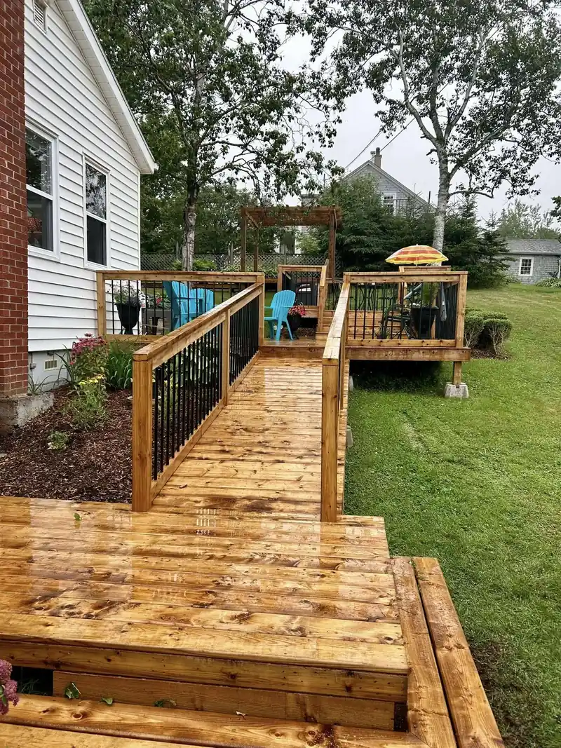 A freshly built cedar deck with wide steps down to a lawn, wet with rain.