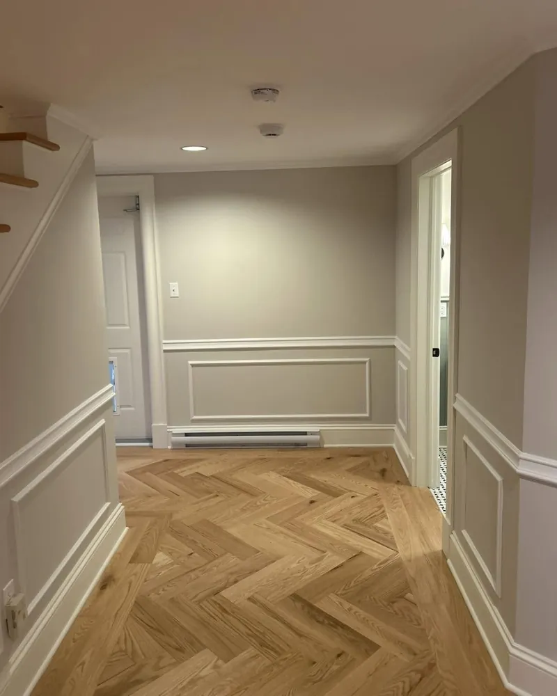 A hallway with a herringbone floor and panelled wainscotting.