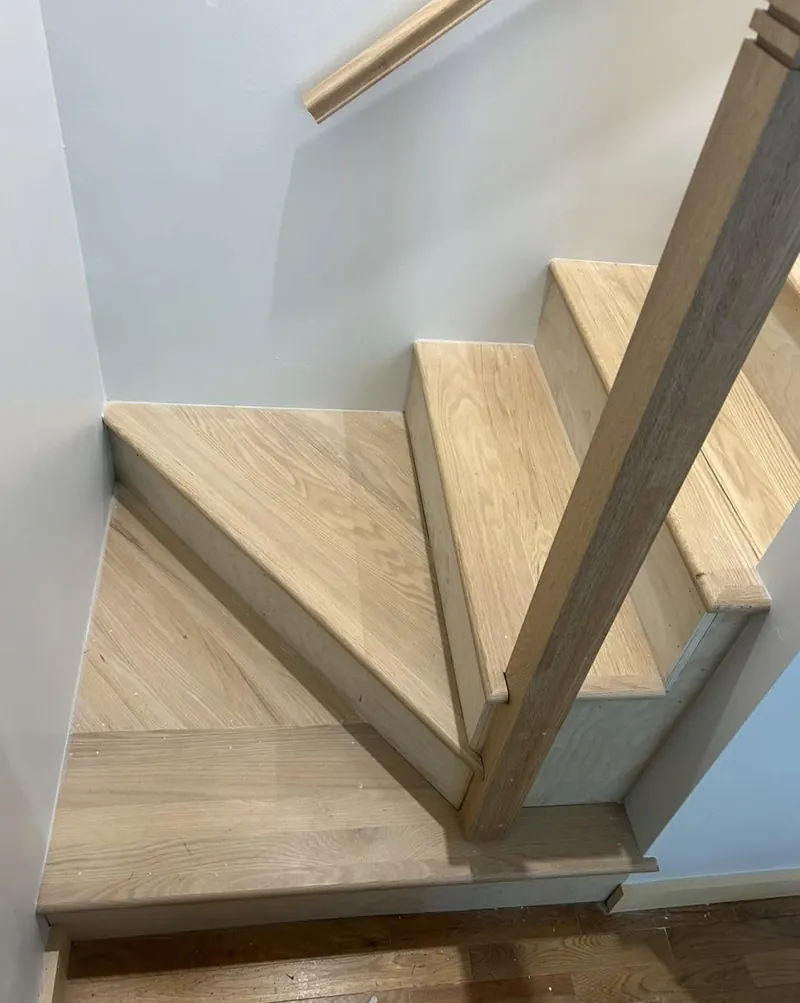 The underside of an open riser stair, oak treads housed into the stringer.