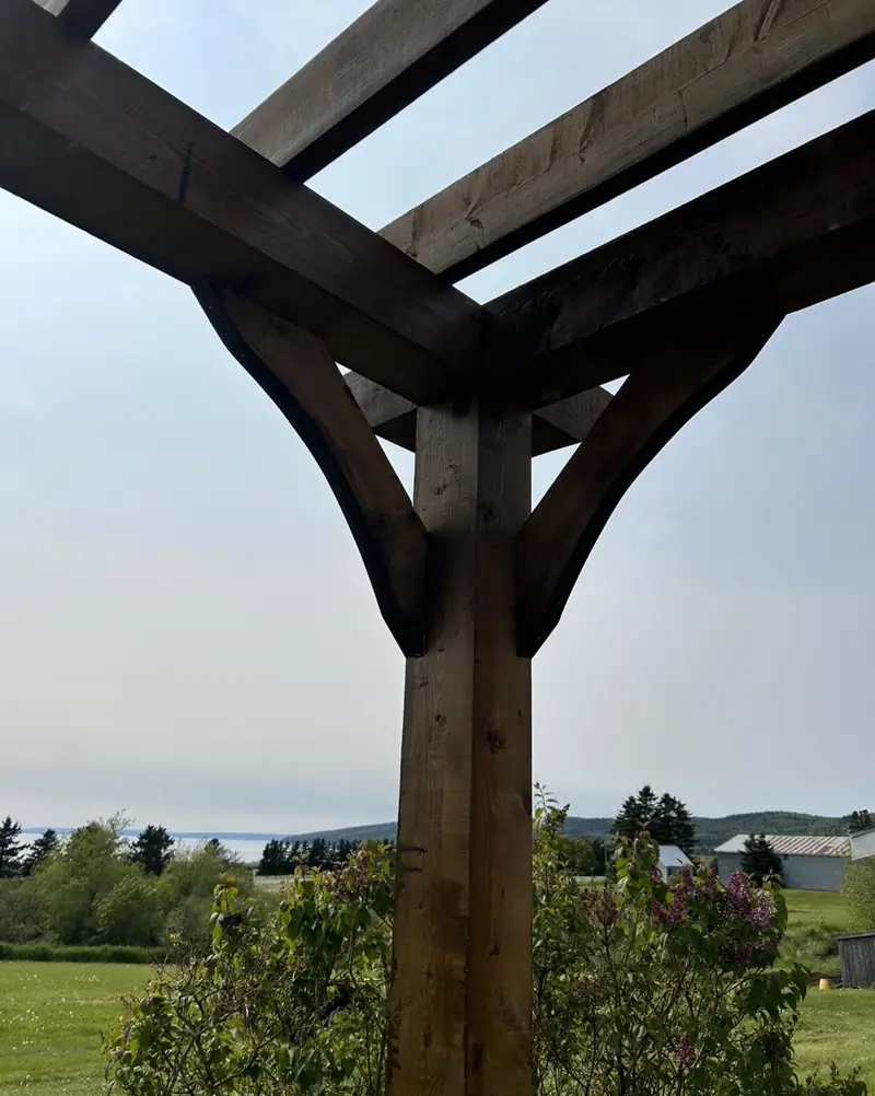 A heavy timber pergola post and beam seen from below against the sky.