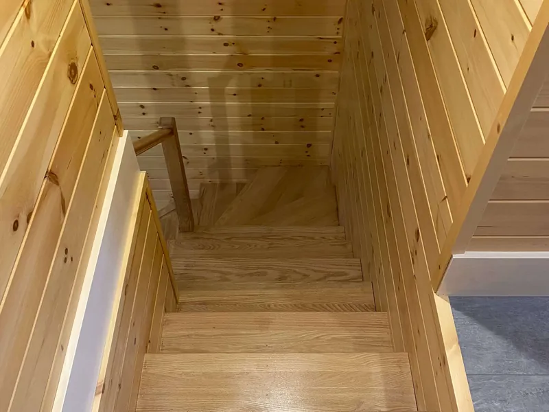 A staircase and landing finished in clear pine boards.