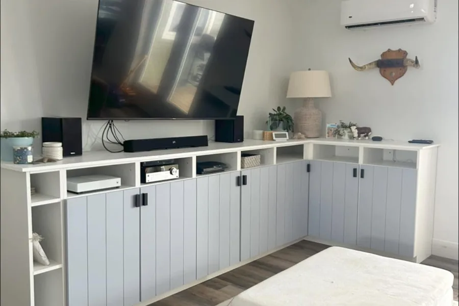 A built-in cabinet and shelving run with beadboard doors wrapping the corner of a living room.